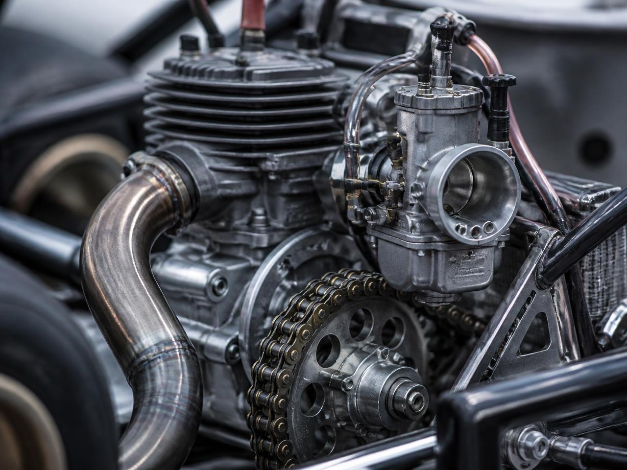Close-up of a karting engine, carburettor, exhaust and sprocket on a race chassis